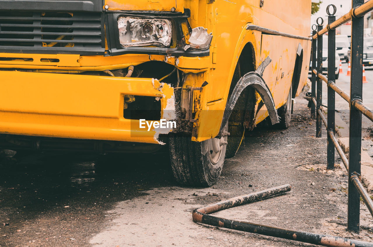 Accident on the road in city with shuttle bus. damaged yellow bus on sidewalk. damaged headlight