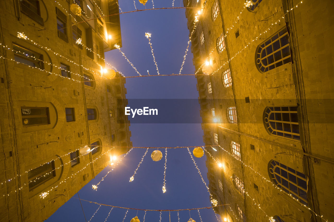 LOW ANGLE VIEW OF ILLUMINATED BUILDINGS AGAINST CLEAR SKY