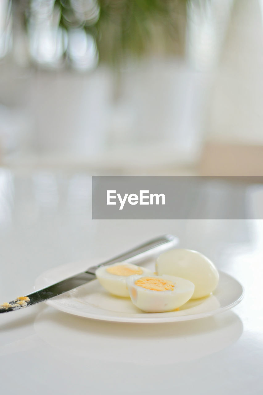 Boiled eggs on a kitchen table, healthy protein rich breakfast. plate, a knife, white background.