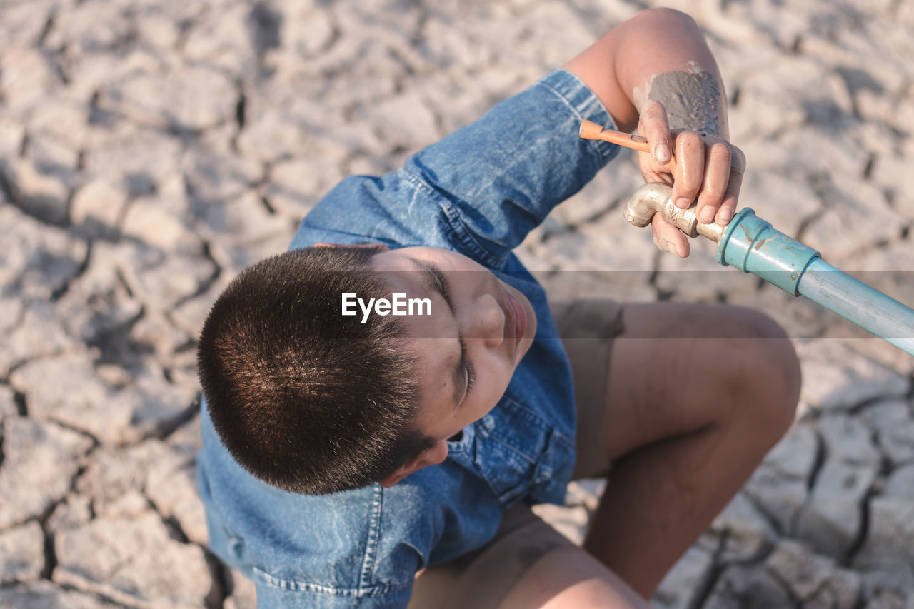 Boy looking at faucet during summer