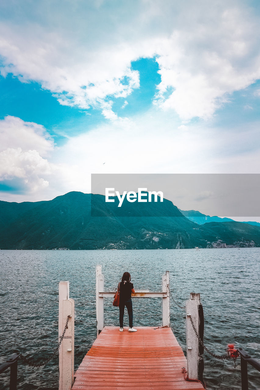 Rear view of woman standing on pier against sky