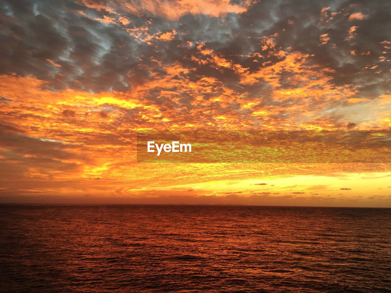 Scenic view of sea against dramatic sky during sunset