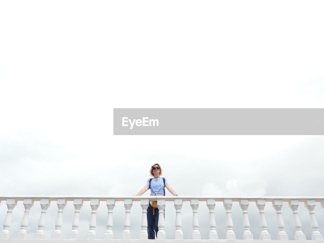 Full length of woman standing on railing against sky