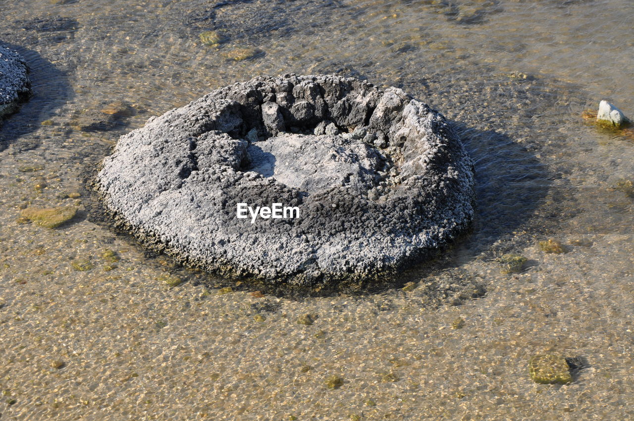 HIGH ANGLE VIEW OF ROCK ON SAND