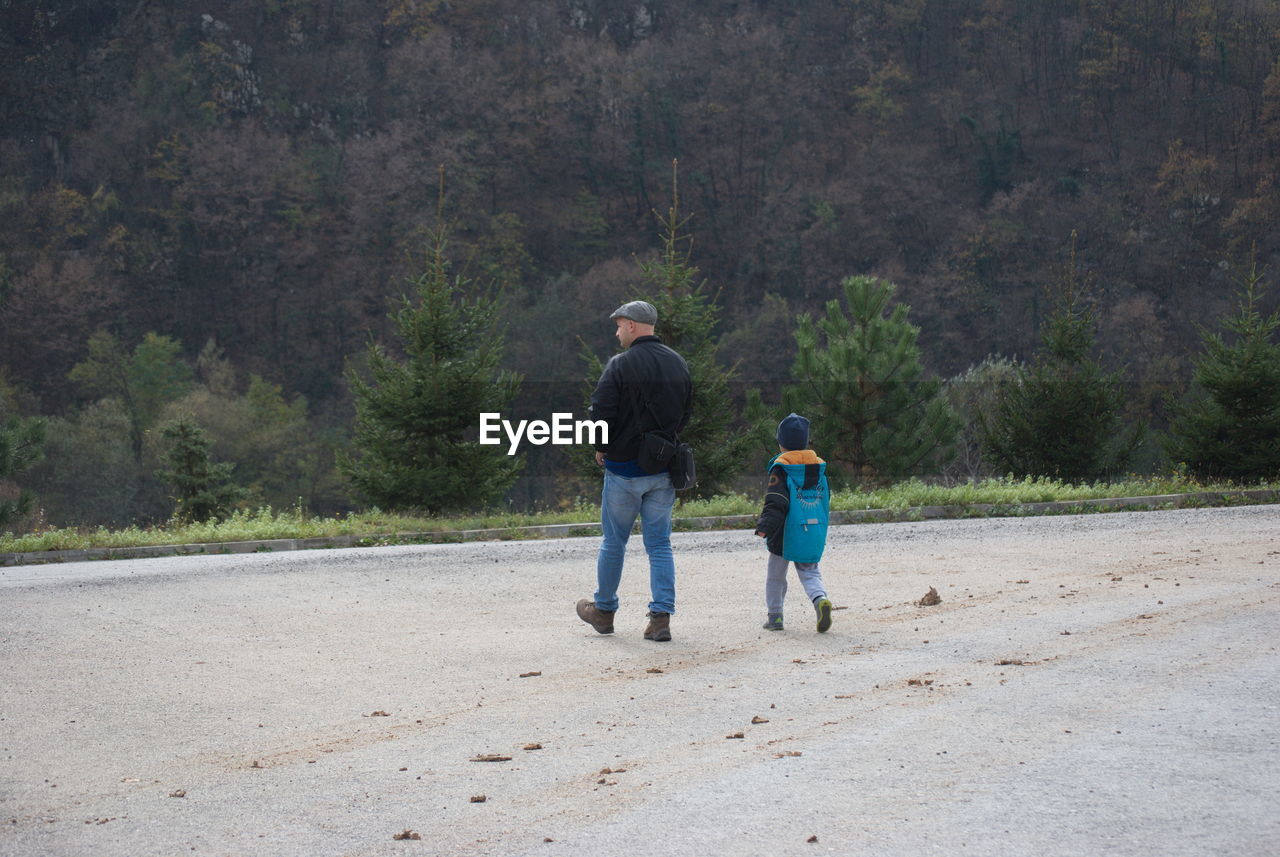 Rear view of father and son walking on road