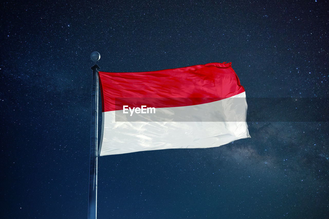 Low angle view of indonesian flag against star field sky