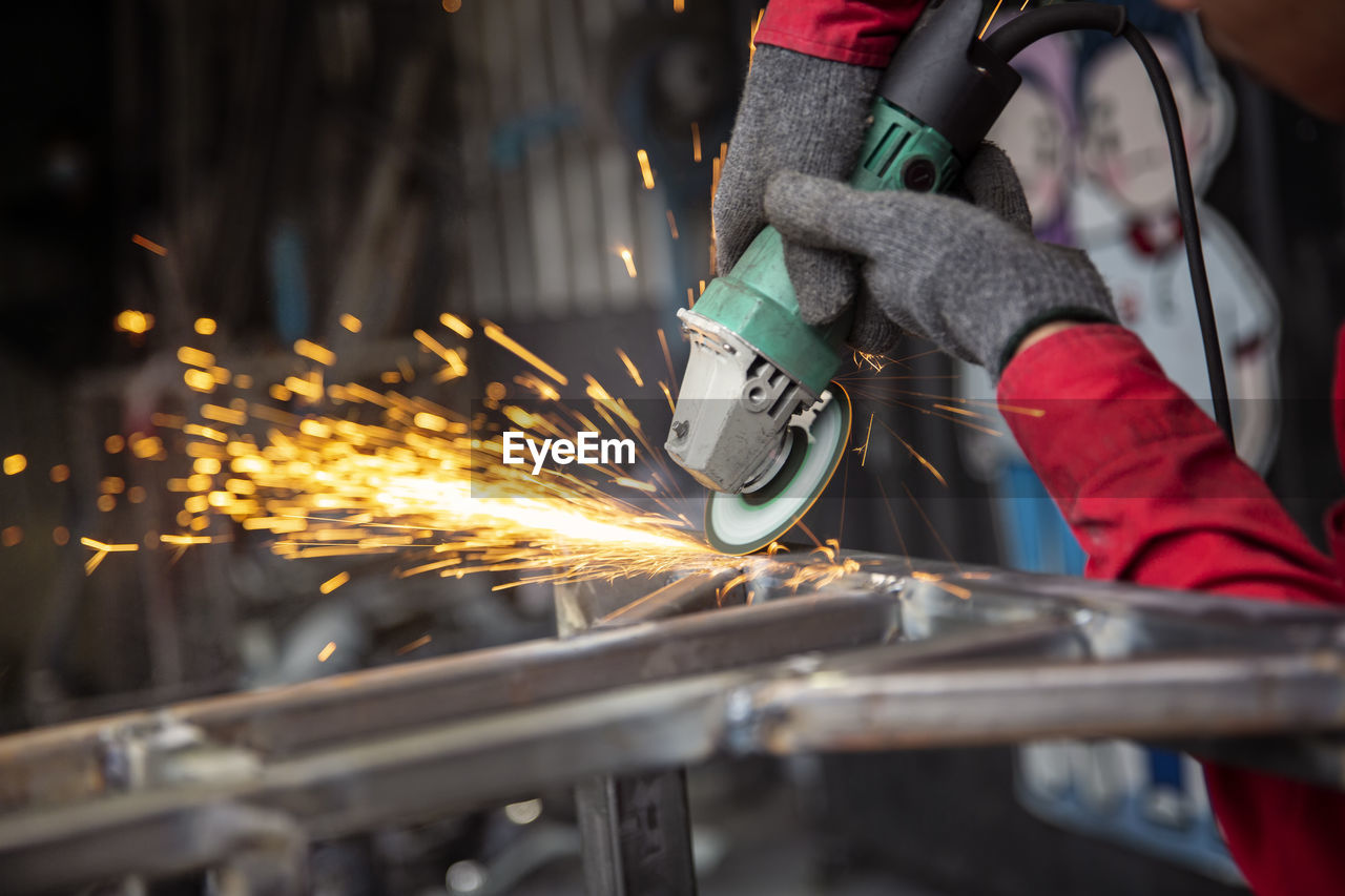 Welder used grinding stone on steel in factory with sparks, welding process at the industrial work