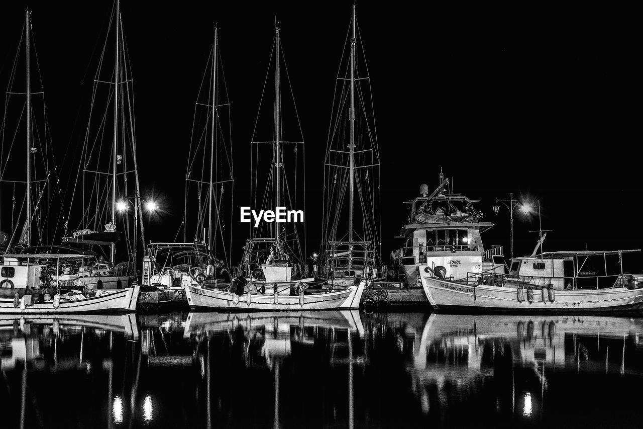 Sailboats moored in harbor at night