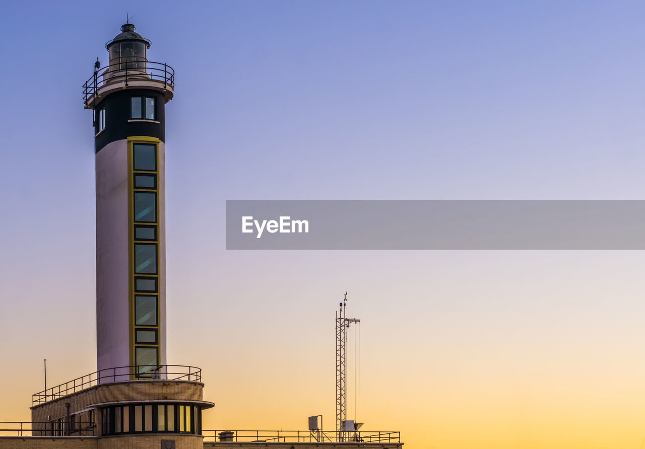 LOW ANGLE VIEW OF LIGHTHOUSE BY BUILDING AGAINST SKY