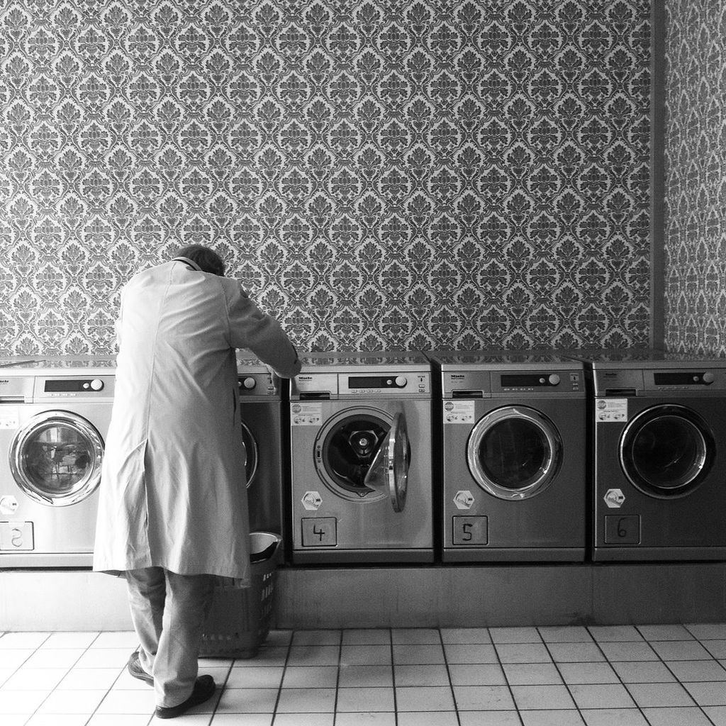 Rear view of man standing by washing machines at laundromat