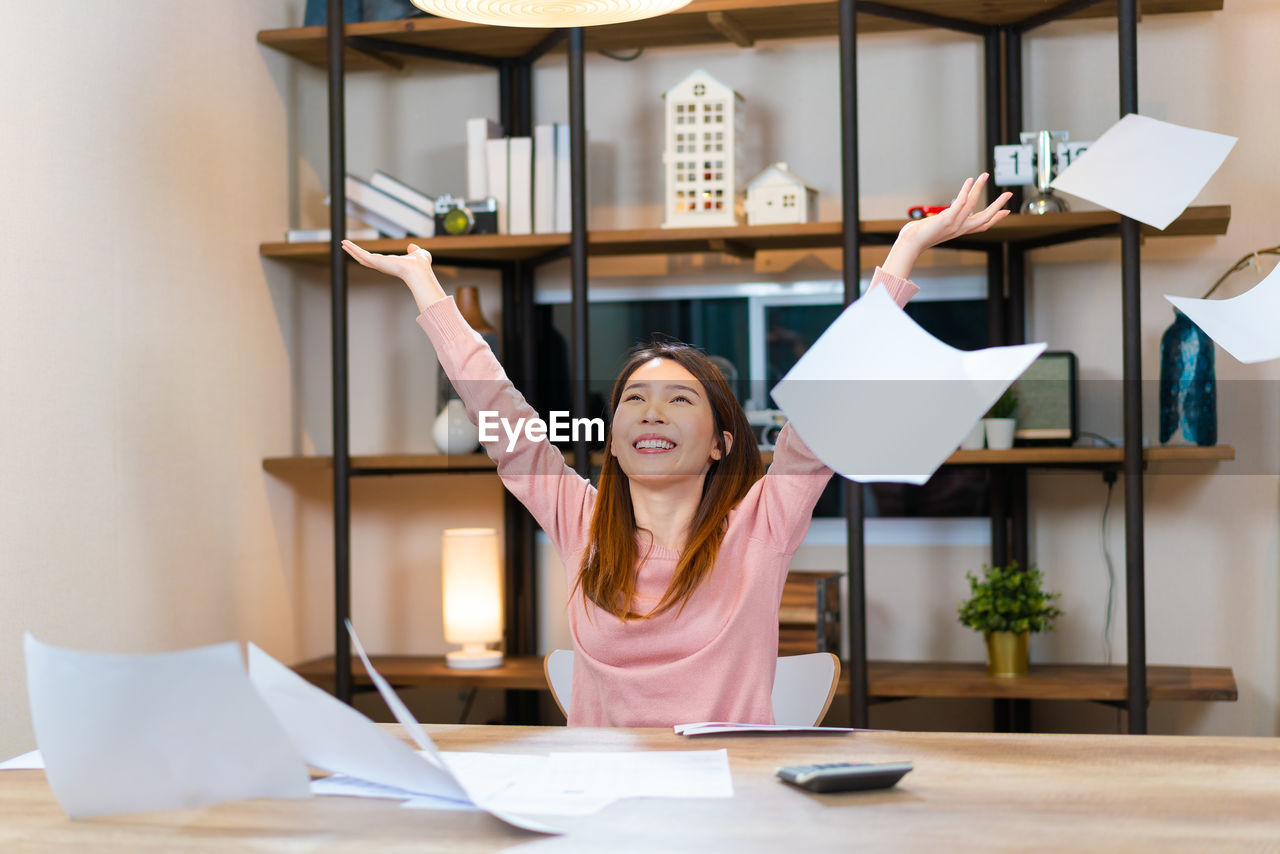 Cheerful asian woman success the job throwing paper sheets in the air. 