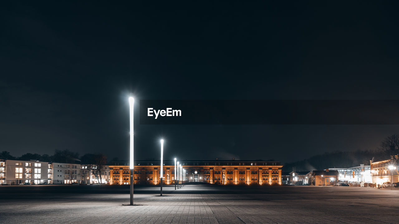 Illuminated street against sky at night