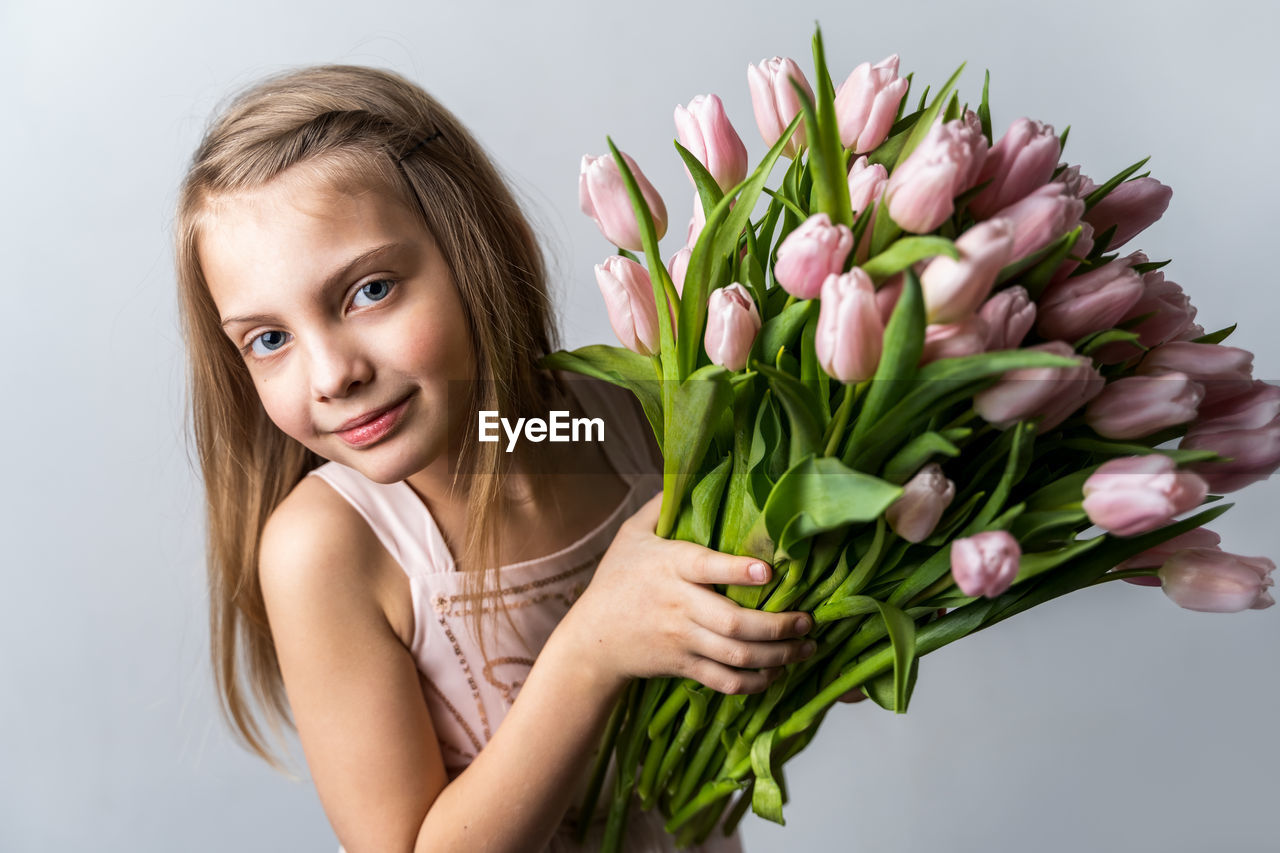 PORTRAIT OF A SMILING YOUNG WOMAN HOLDING BOUQUET OF FLOWER