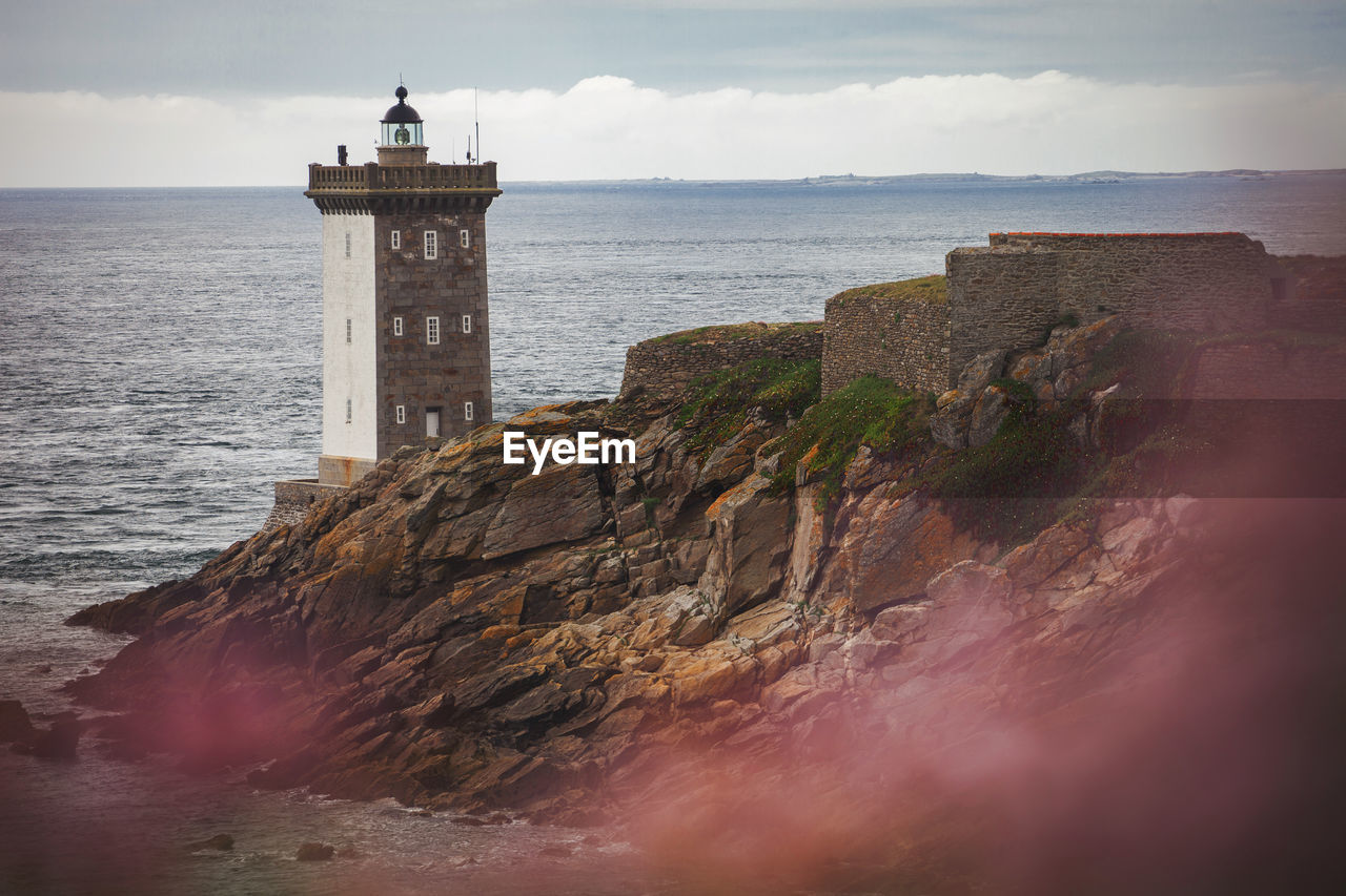 Lighthouse by sea against sky