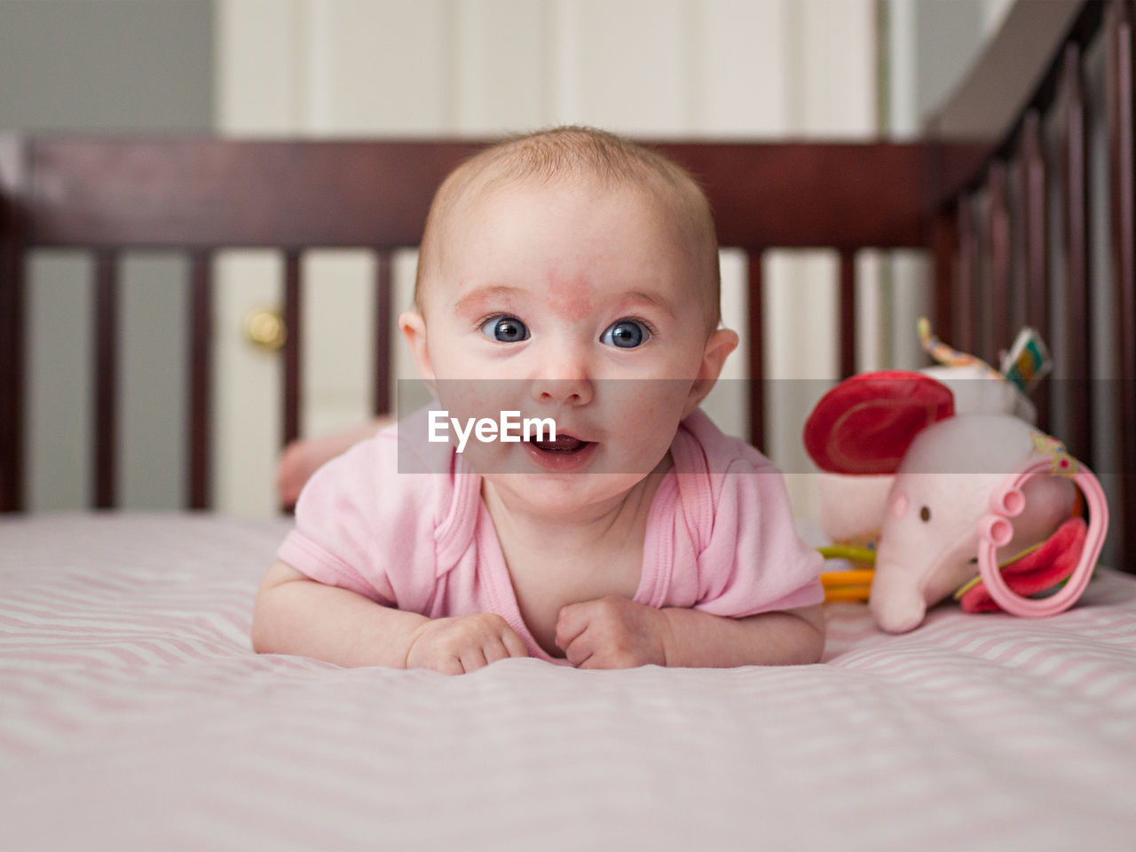 Close-up of cute baby girl smiling on crib