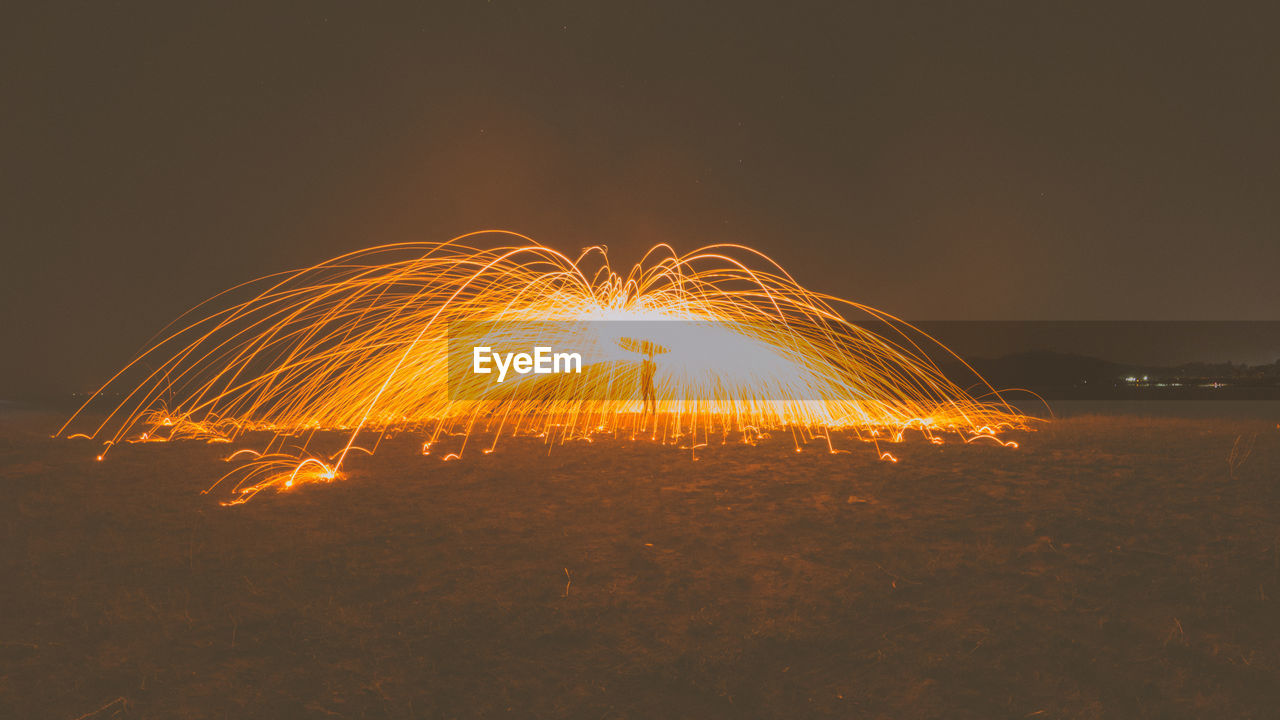 Light trails on field against sky at night