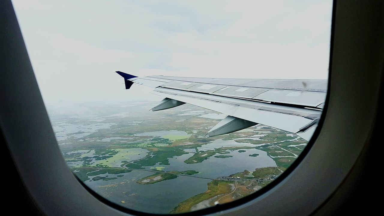 Airplane wing and landscape seen through window