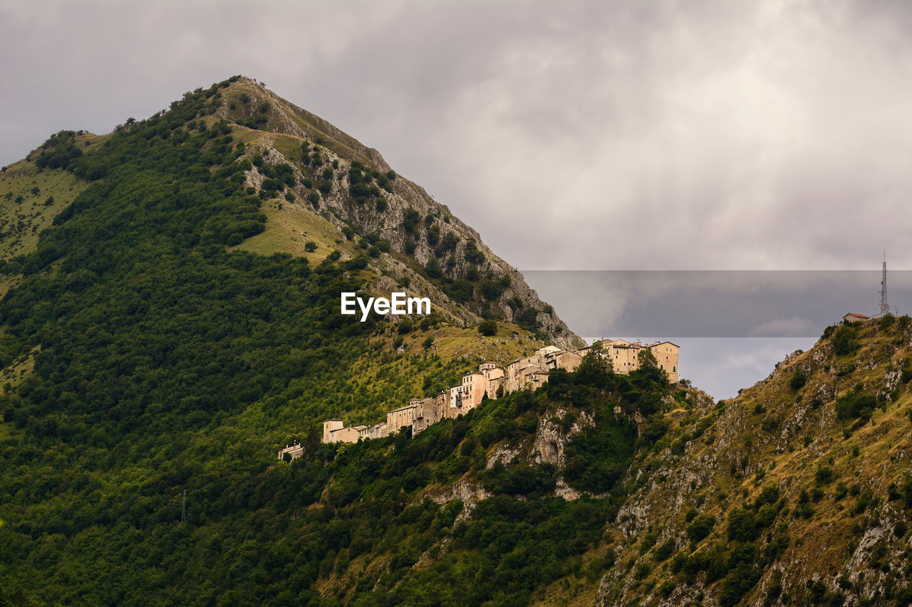 SCENIC VIEW OF MOUNTAINS AND TREES AGAINST SKY