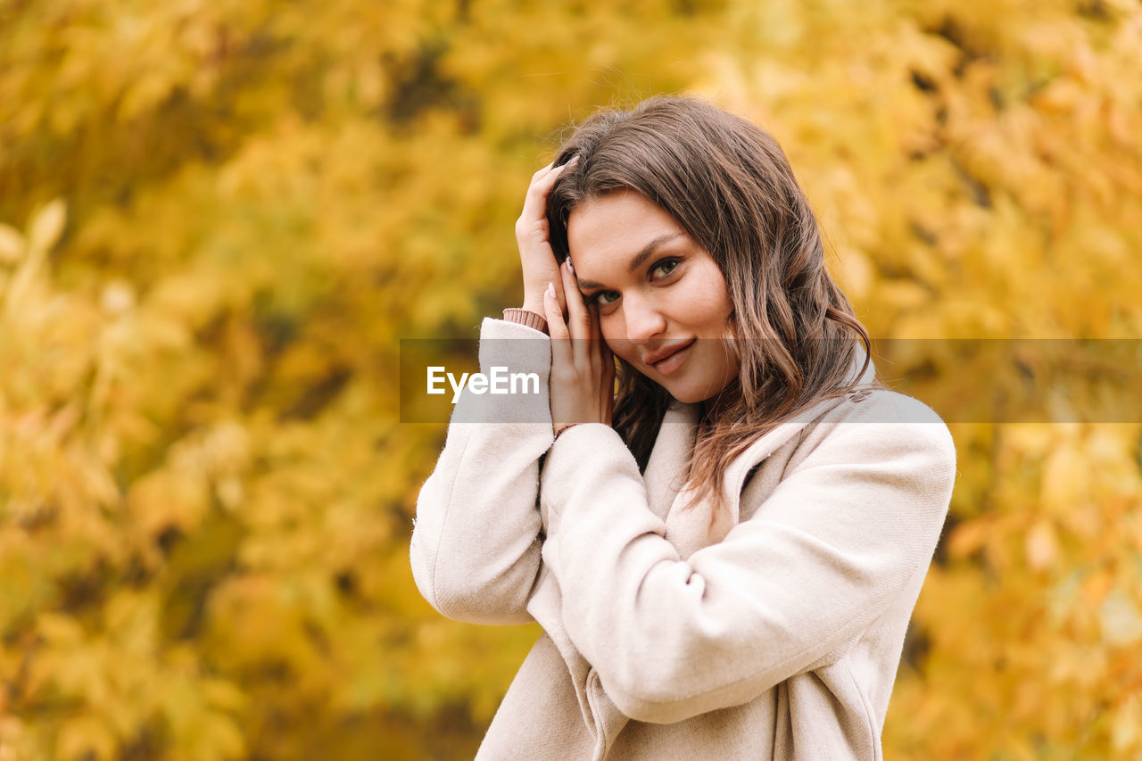 A beautiful happy girl in casual clothes is walking in the autumn outdoor park drinking coffee