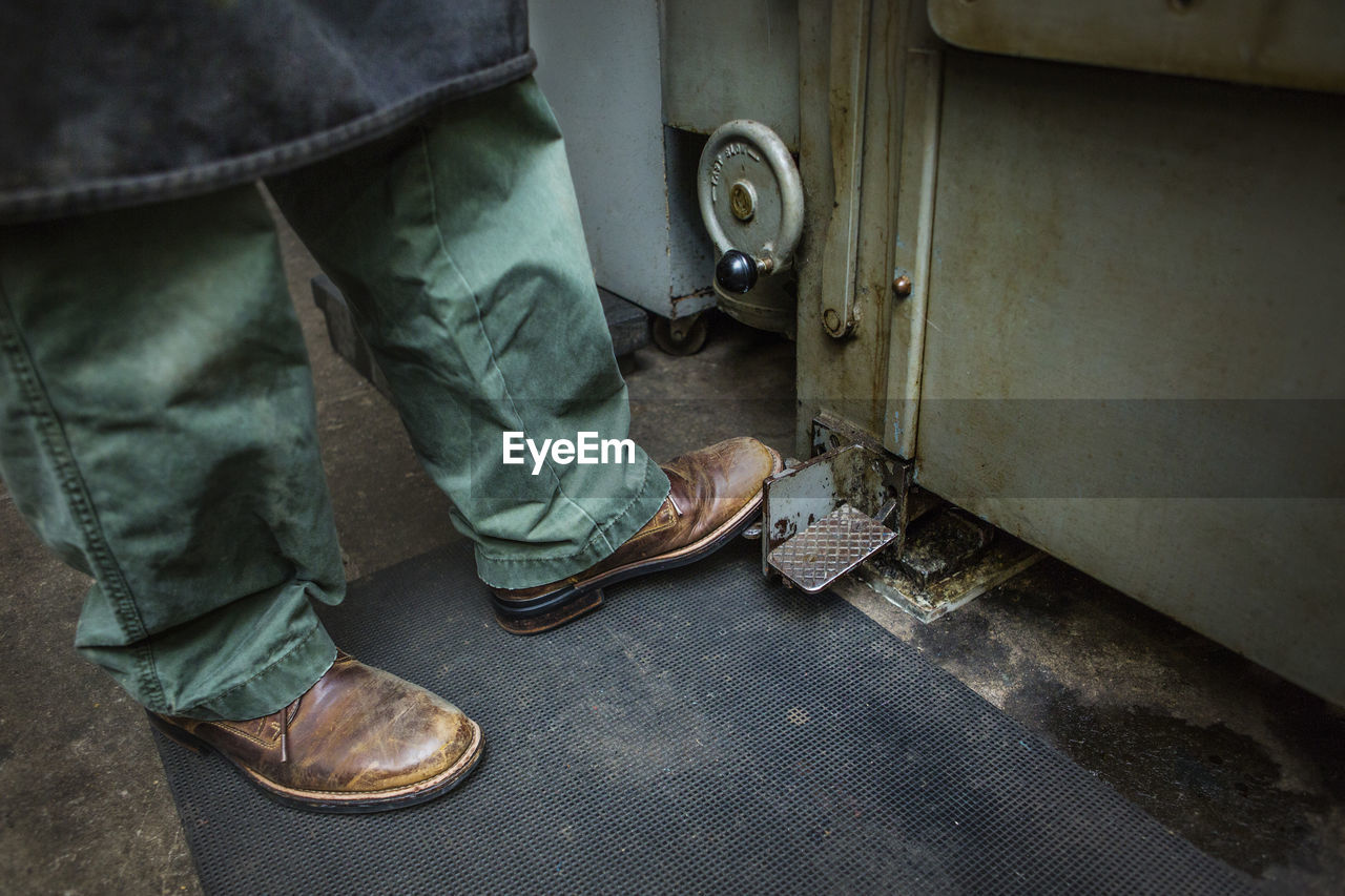 Low section of worker working on machinery at workshop