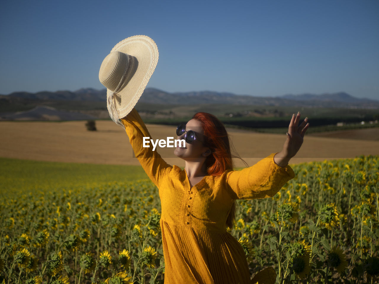 Rear view of woman wearing hat standing on field against sky