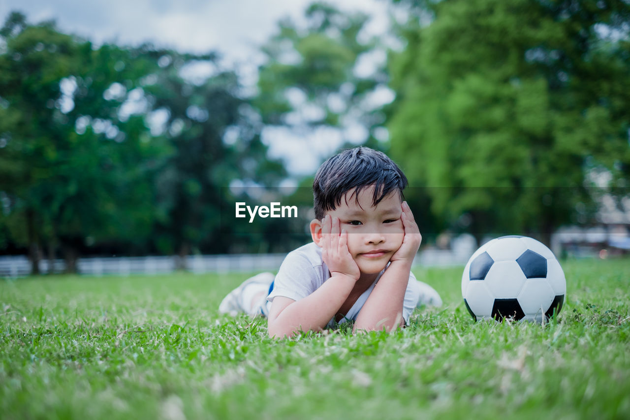 PORTRAIT OF A BOY WITH BALL ON GRASSLAND