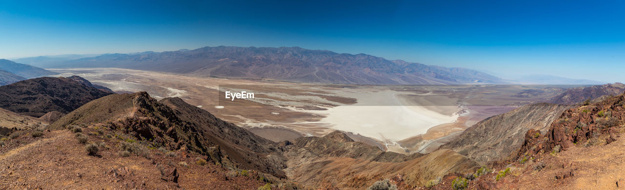 Panoramic view of desert against blue sky