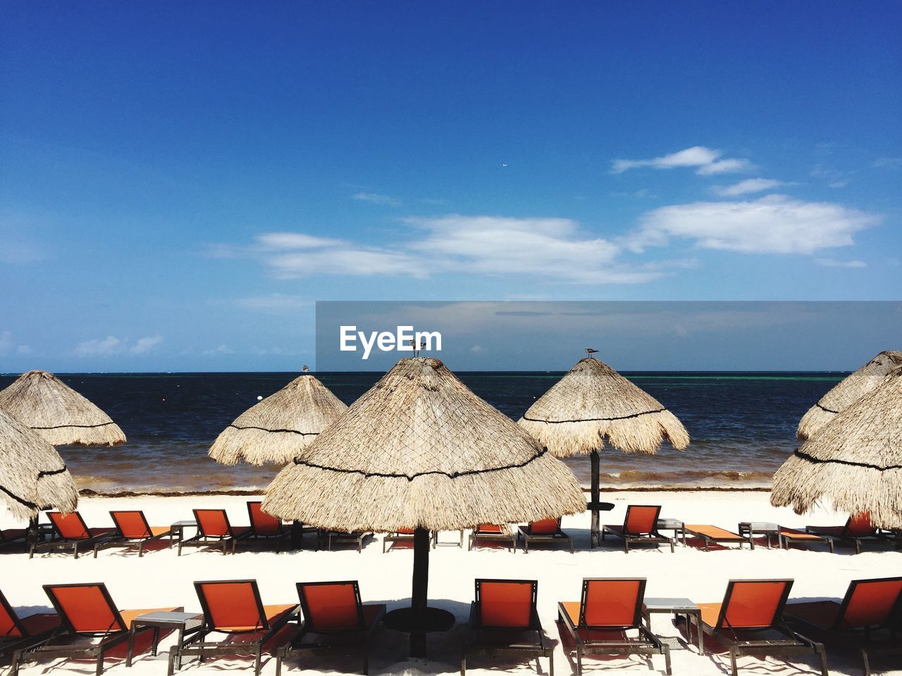 Sun loungers with canopies in row against calm sea