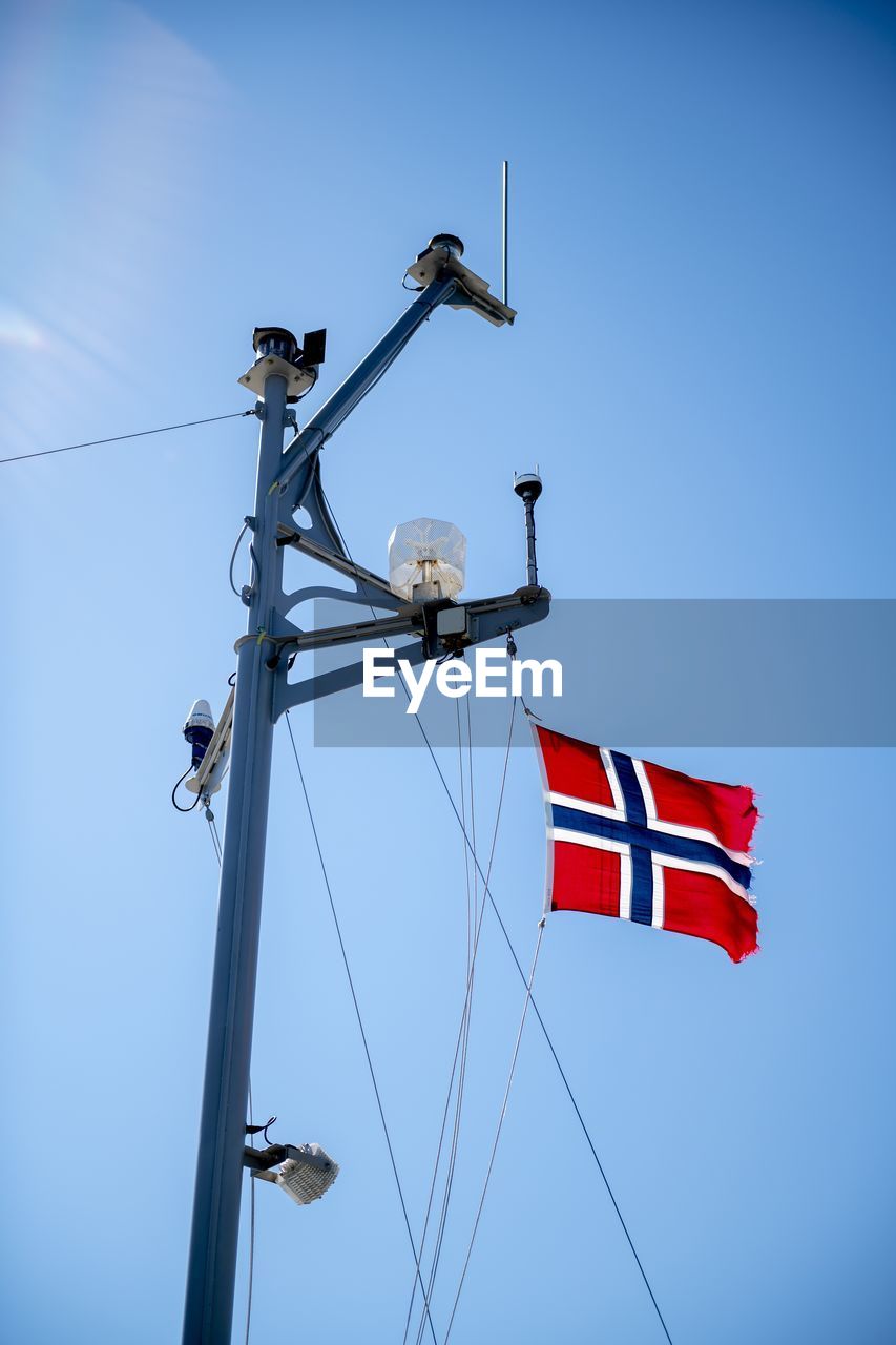 Flag of norway attached to ship's mast, ruffled by wind, flutters beautifully in the breeze.