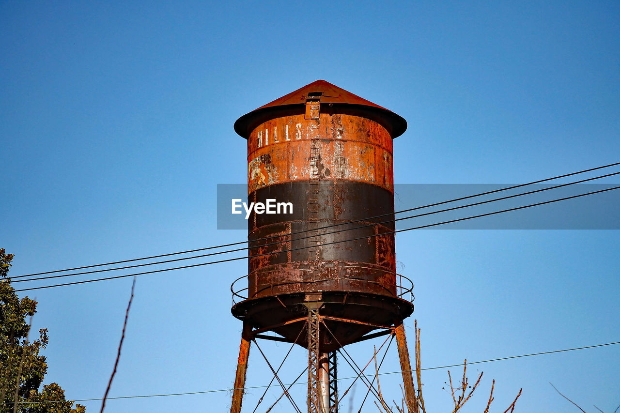 Low angle view of rusty water tower against clear sky