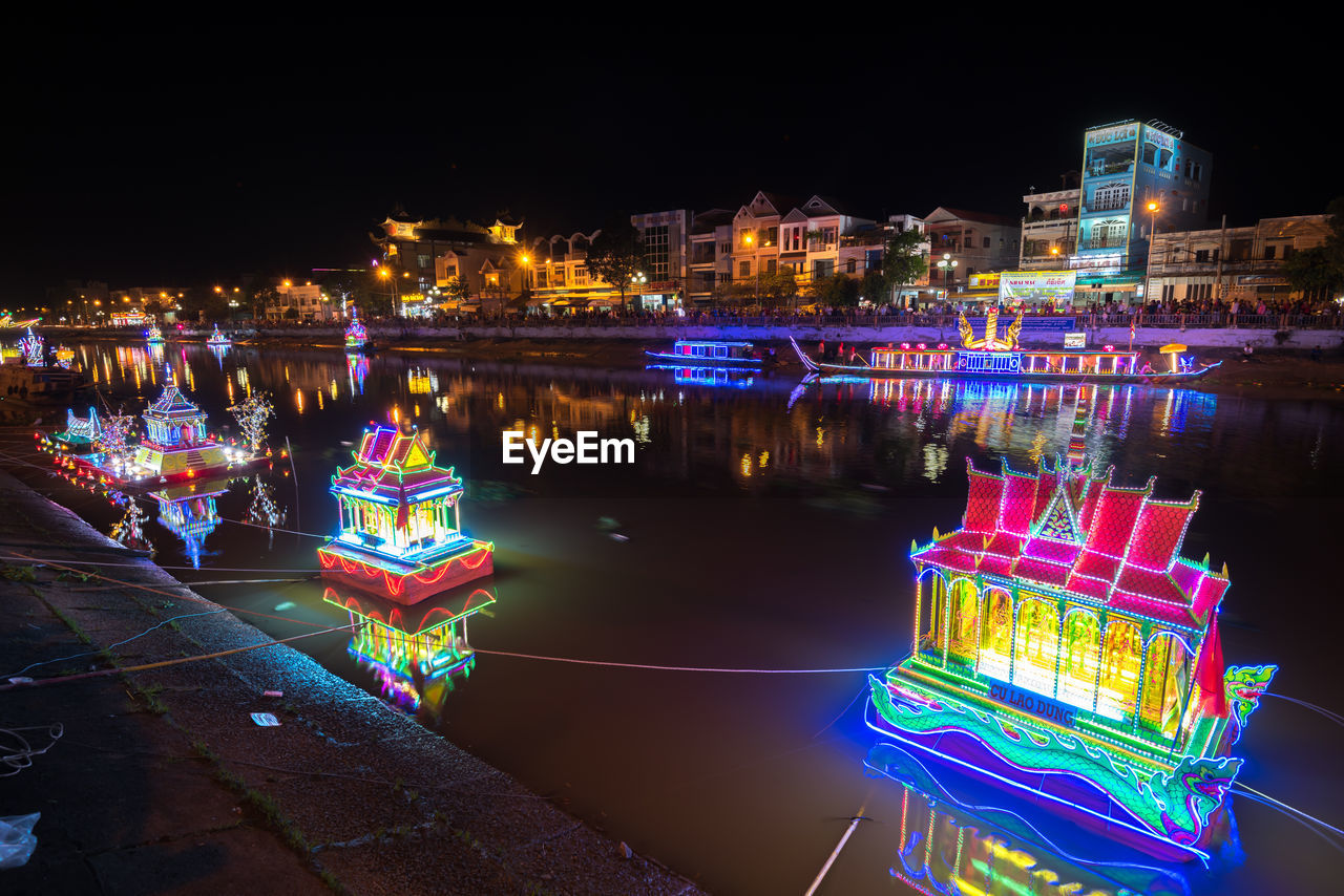 Illuminated buildings by river in city at night soc trang