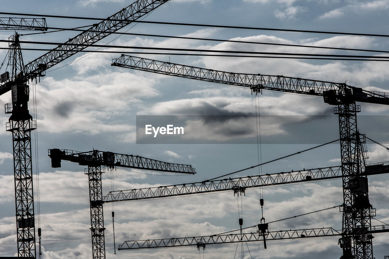 LOW ANGLE VIEW OF CRANES AT CONSTRUCTION SITE AGAINST SKY