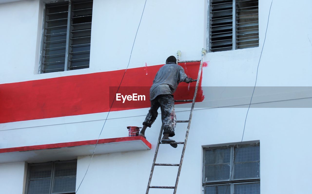 LOW ANGLE VIEW OF MAN WORKING AGAINST BUILDING