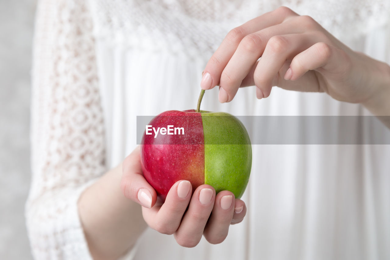 Girl holding a red-green apple in her hand