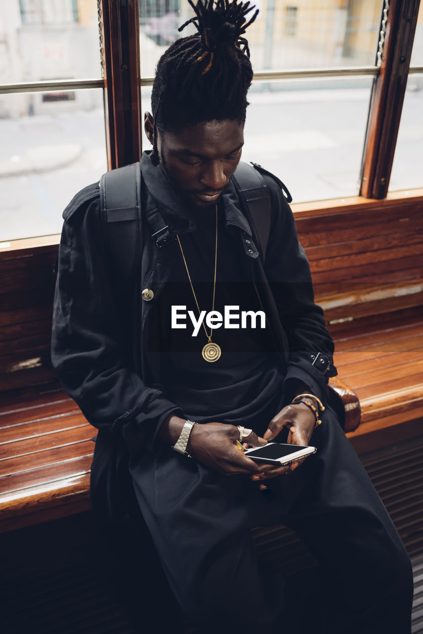 Young man using mobile phone while sitting in tram