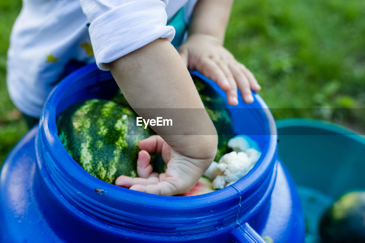 Midsection of boy by fruits in container