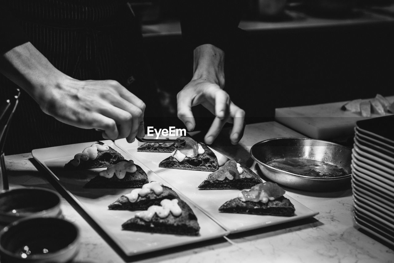 Midsection of man garnishing food on table