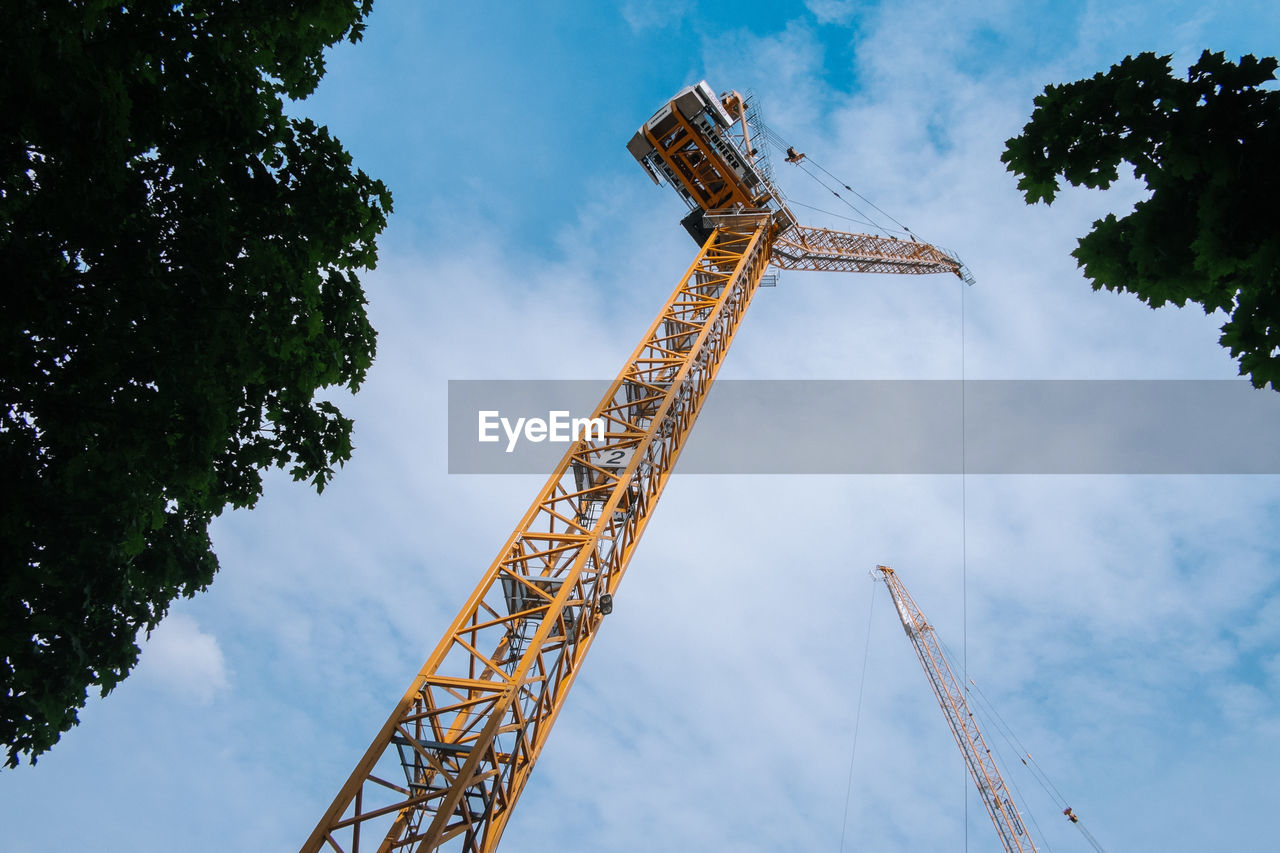 Low angle view of crane against cloudy sky