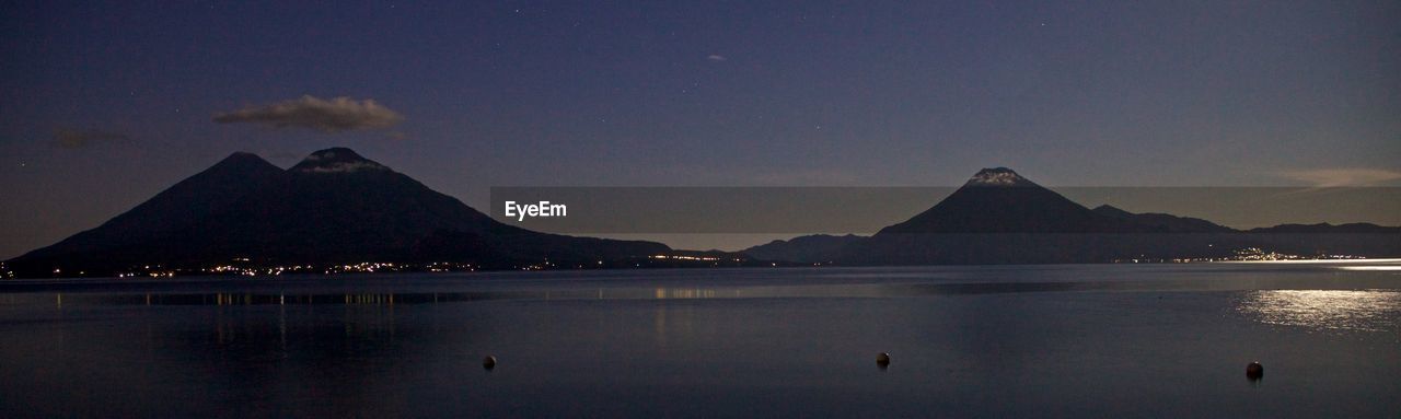 SCENIC VIEW OF LAKE AND SILHOUETTE MOUNTAINS AGAINST SKY AT NIGHT