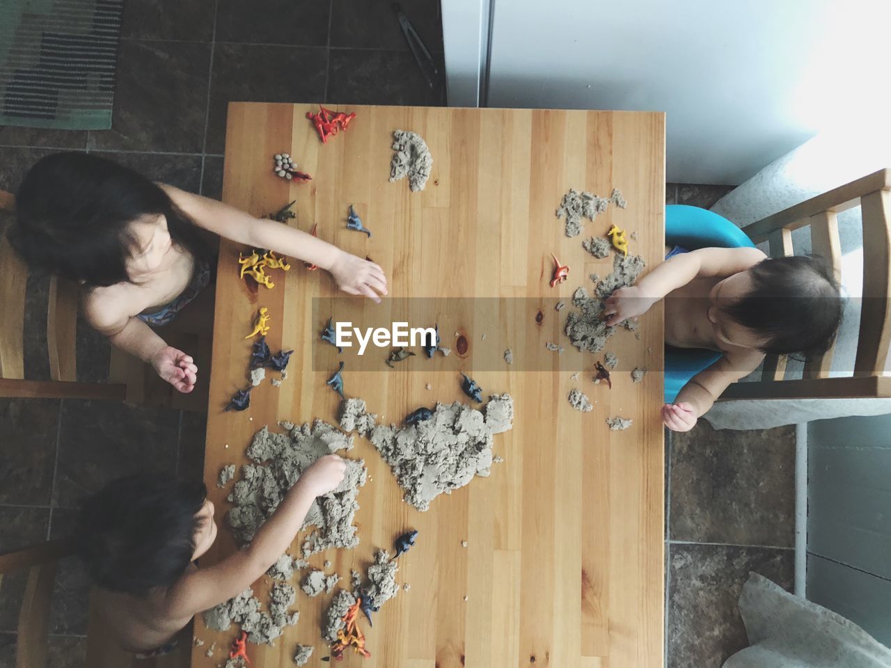High angle view of shirtless siblings playing with toys at table