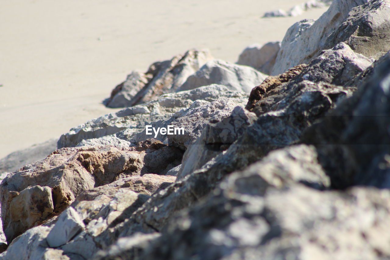 CLOSE-UP OF ROCKS ON BEACH AGAINST SKY