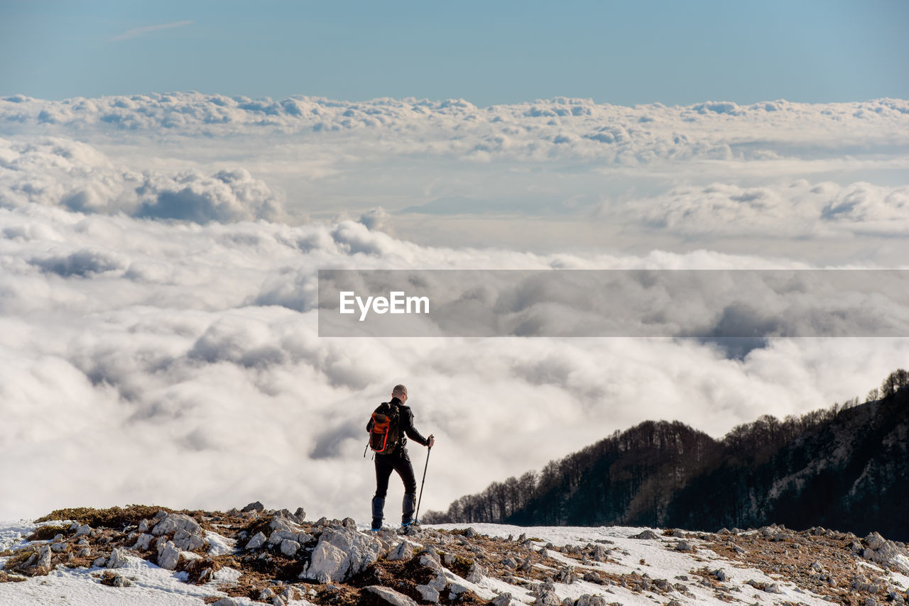 Man standing on land against cloudscape during winter