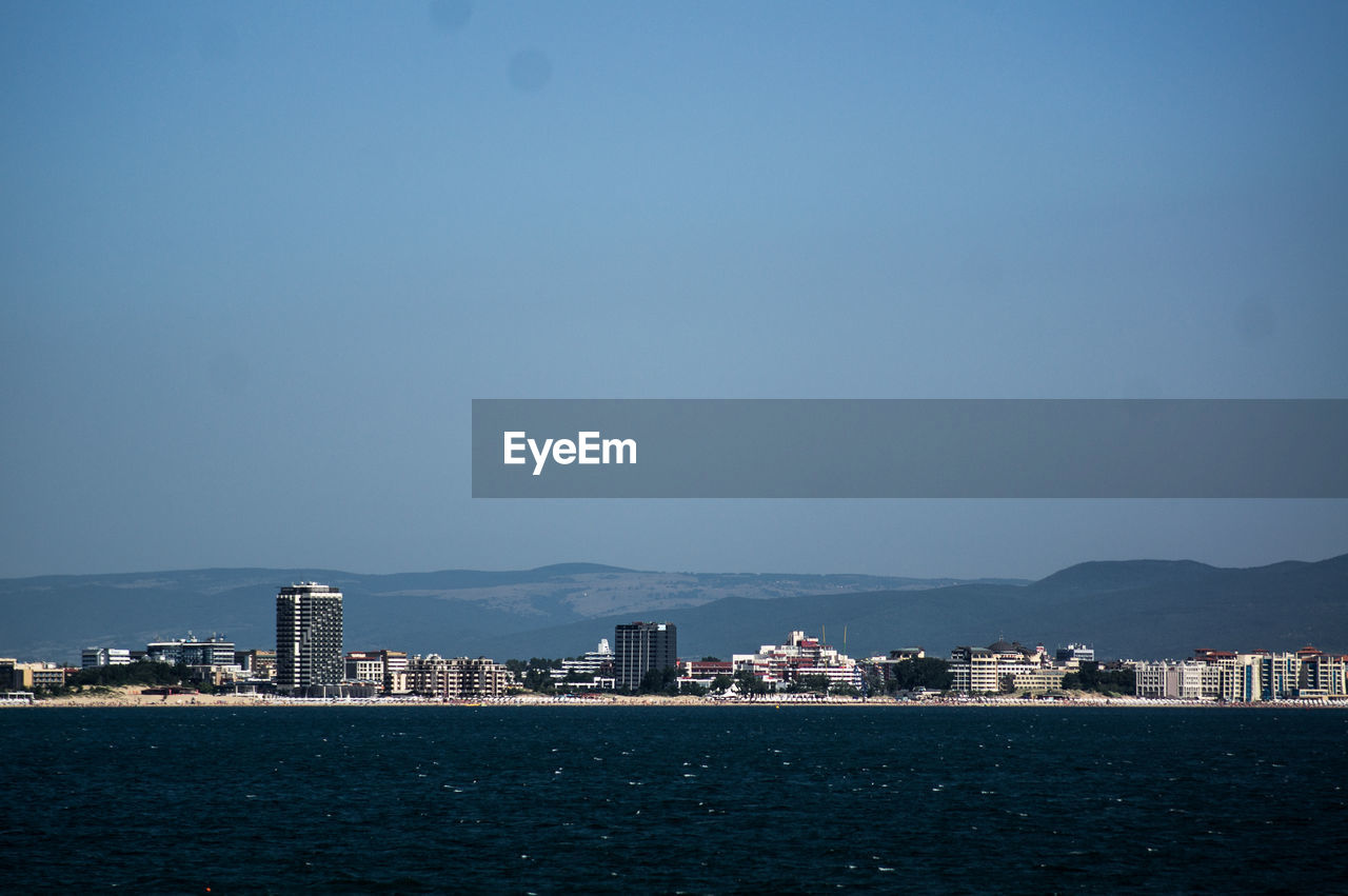 SCENIC VIEW OF SEA BY CITY AGAINST CLEAR SKY