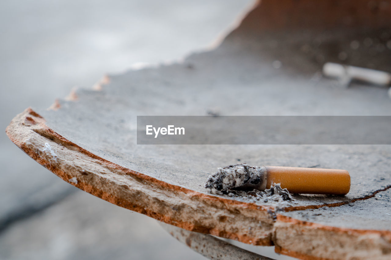 Close-up of cigarette butt on broken surface