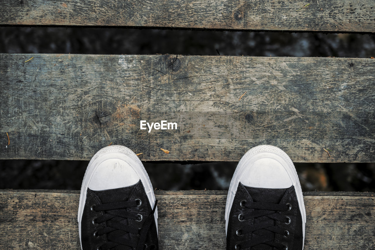 Directly above shot of canvas shoes on wooden footbridge