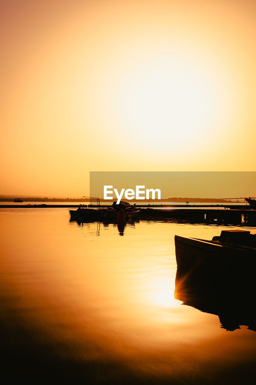 water, sunset, sky, reflection, dawn, horizon, silhouette, nature, beauty in nature, tranquility, sea, orange color, scenics - nature, transportation, nautical vessel, tranquil scene, sun, sunlight, mode of transportation, evening, no people, copy space, vehicle, idyllic, outdoors, afterglow, horizon over water, clear sky
