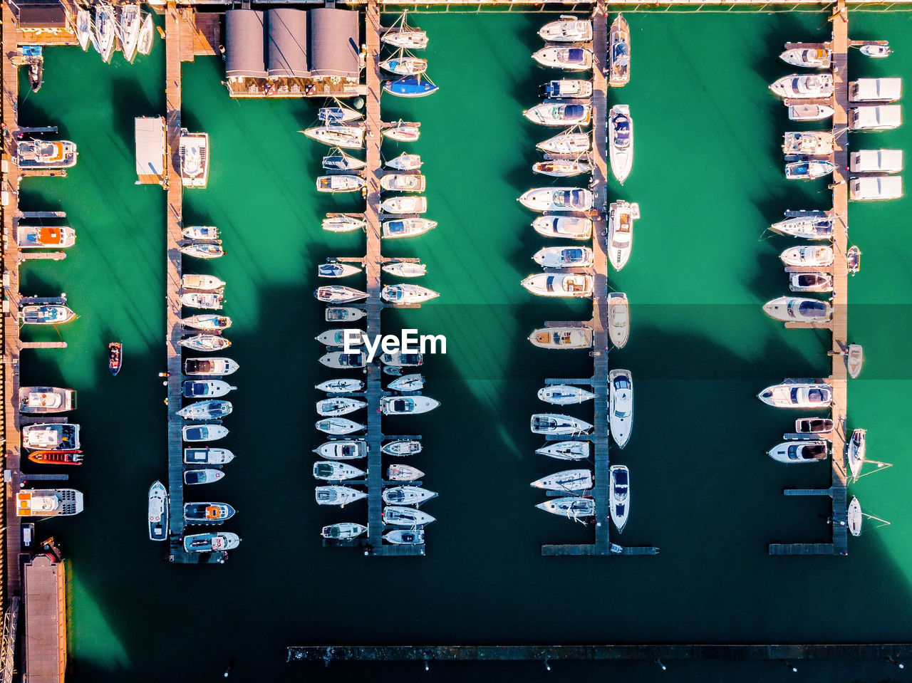 Aerial view of boats moored by piers at harbor in city