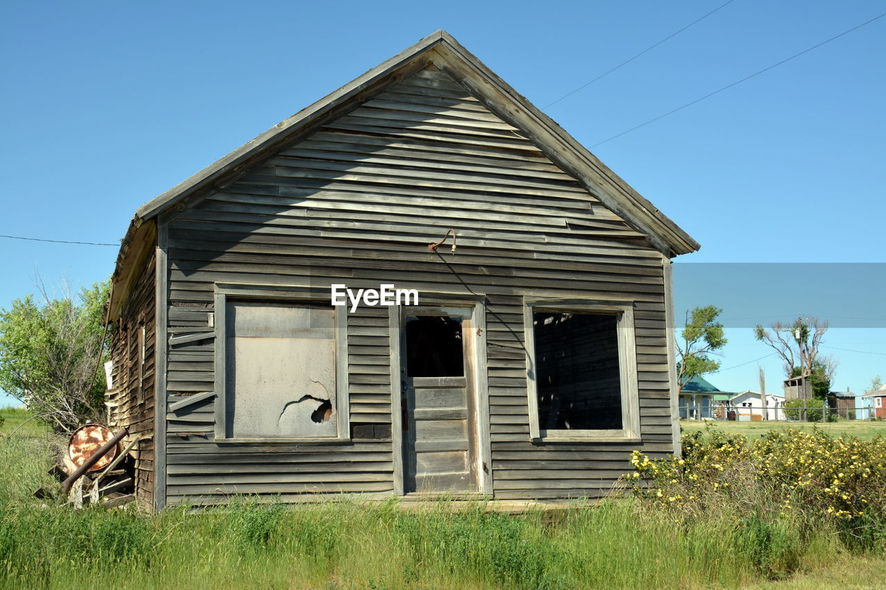 LOW ANGLE VIEW OF OLD HOUSE AGAINST BLUE SKY