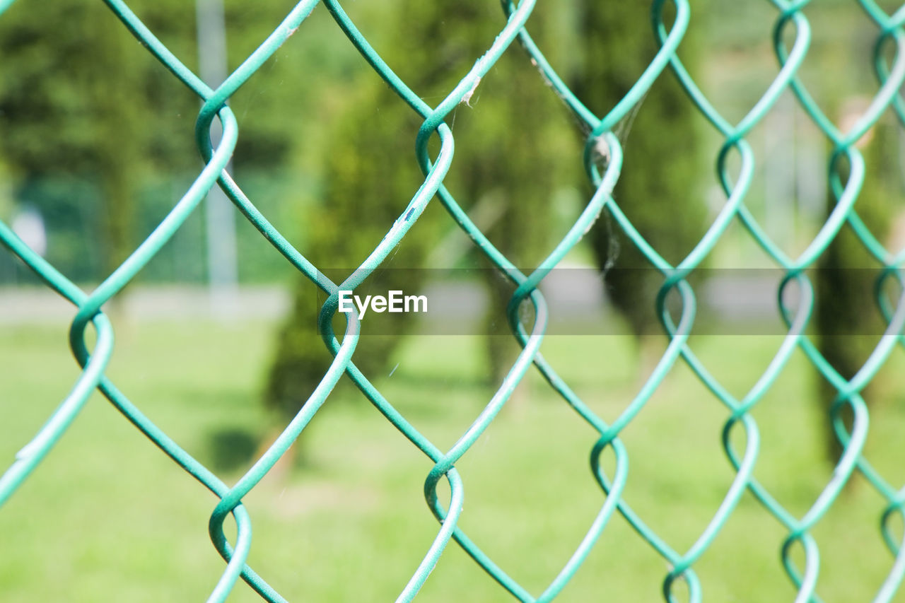 CLOSE-UP OF CHAINLINK FENCE ON FIELD