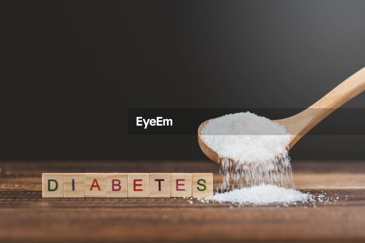 Sugar poured on a wooden table with diabetes word. concept of diabetes and unhealthy eating.